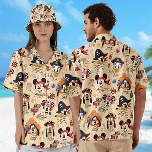 May include: Beige button-down shirt and bucket hat with a repeating pattern of cartoon pirate characters, including Mickey Mouse, Donald Duck, and Goofy. The design includes pirate hats, treasure chests, and nautical elements.