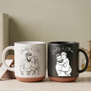 May include: Two ceramic mugs with illustrations and text. One mug is white with a brown base, featuring a father and daughter. The other mug is black with a brown base, featuring a father and son. Text on the mugs reads "Daddy & Chloe" and "Daddy & Ethan."