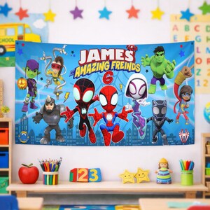 Op de afbeelding: Een rechthoekige blauwe stoffen banner met de tekst "JAMES and his AMAZING FREINDS" en een groot rood cijfer 6. Het ontwerp bevat cartoonillustraties van diverse superhelden, waaronder Spider-Man, Ghost-Spider en de Hulk.