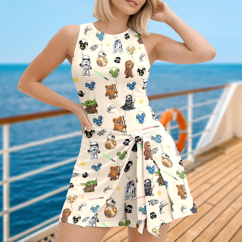 Puede incluir: Vestido sin mangas color crema con un estampado de personajes de Star Wars. El vestido incluye im&aacute;genes de personajes como Yoda, Darth Vader y R2-D2, junto con globos y estrellas. El vestido tiene una falda cruzada.