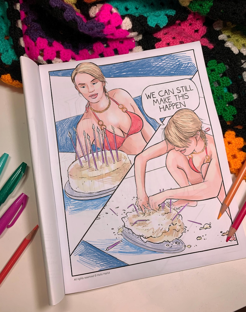 May include: A coloring book page featuring a woman in a red bikini with a birthday cake. The text in the speech bubble says, "WE CAN STILL MAKE THIS HAPPEN." The page is open, with colored pencils and pens visible.