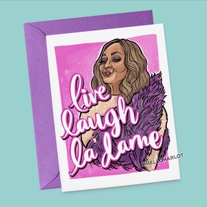 May include: A pink and purple greeting card with a cartoon illustration of a woman with blonde hair wearing a sparkly top and a purple feather boa. The text on the card reads "live laugh la dame" and "@hello_harlot".