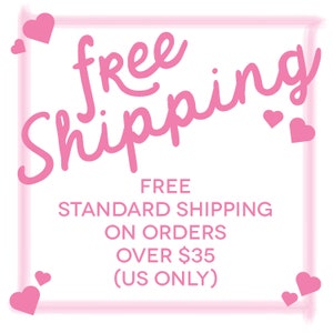May include: A white background with pink text that reads "free shipping" in a cursive font. Below, smaller text states "FREE STANDARD SHIPPING ON ORDERS OVER $35 (US ONLY)". Pink hearts are scattered around the text.
