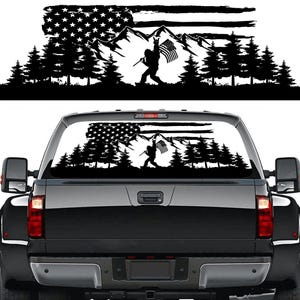 Puede incluir: Gráfico en blanco y negro de una escena de montaña con una bandera estadounidense y una silueta de una persona sosteniendo una bandera. El diseño incluye pinos y una cordillera, adecuado para una ventana de coche.