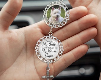 May include: A silver car charm featuring a photo of a white dog in a decorative frame. The charm has a second frame with the text "Once by My Side Forever in My Heart Cooper" and a small cross pendant.