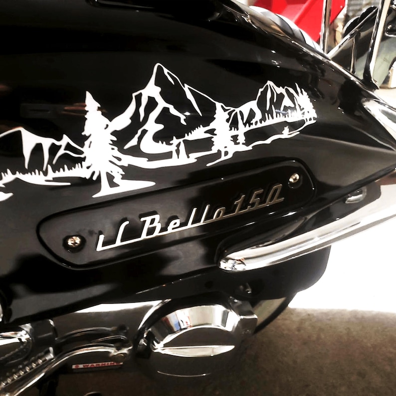 May include: A black motorcycle with a white mountain and tree decal on the back fender. The motorcycle has a chrome rear fender and a chrome exhaust pipe. The motorcycle has a silver emblem that says "Bella 150".