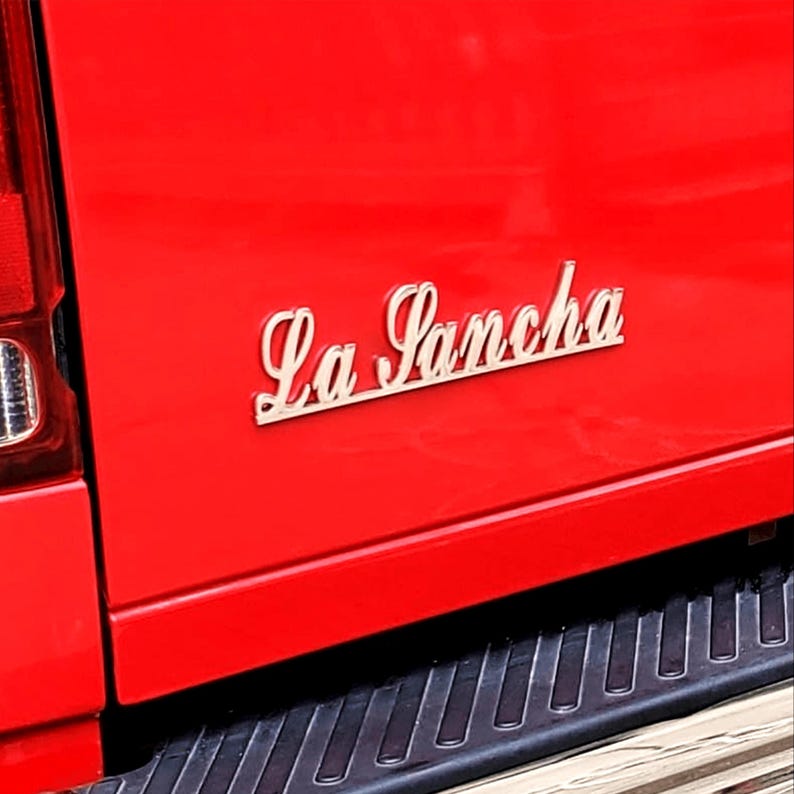 May include: A red truck with a silver "La Sancha" emblem on the back.