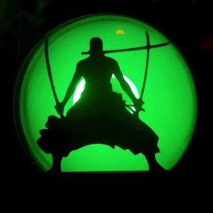 Peut inclure: Silhouette noire d'une figurine tenant trois épées, sur fond vert vif circulaire. La figurine est en position de combat, les épées étant positionnées pour le combat. Le design est un contraste saisissant de clair et d'obscur.