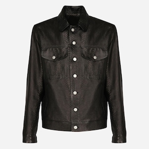May include: A black jacket featuring a textured snakeskin pattern throughout. The garment includes a pointed collar, a front button-down closure with silver-toned buttons, long sleeves with buttoned cuffs, and two chest pockets with buttoned flaps.