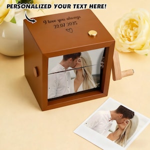 May include: A brown wooden music box with a photo of a couple kissing. The box has a crank and a small gold button. The text "I love you always 22.07.2025" is engraved on the top. The words "PERSONALIZED YOUR TEXT HERE!" are at the top.