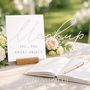 Może przedstawiać: Scena makiety z białym znakiem z napisem "Mockup", "JPG + PSD" i "Smart Object" na drewnianym stojaku. Otwarty notatnik i długopis leżą na stole, wraz z kompozycjami kwiatowymi z róż i zieleni.