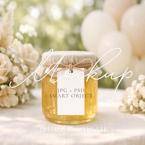 May include: A glass jar filled with golden honey, sealed with a beige fabric lid and a small tag. The jar is on a white surface, with white flowers and balloons in the background. The tag reads "JPG + PSD SMART OBJECT".