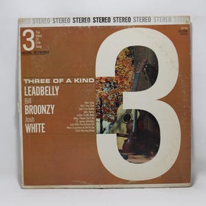 May include: Vintage vinyl record album cover for "Three of a Kind" featuring Leadbelly, Bill Broonzy, and Josh White. The cover is brown with a large white number "3" and a partial image of a guitar. The album title and artist names are in white text.