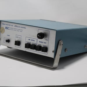 May include: A blue and silver Media Master 400 Dissolve Control device. The device has a series of black buttons and a large black knob. The front panel has the text "Media Master 400 Dissolve Control". The device has a silver metal handle.