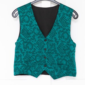Könnte beinhalten: Eine ärmellose Weste mit einer leuchtend türkisfarbenen Grundfarbe und einem sich wiederholenden dunkelgrünen geometrischen Linienmuster. Das Kleidungsstück hat einen V-Ausschnitt, eine Knopfleiste mit vier dunklen Knöpfen und zwei kleine Leistentaschen.