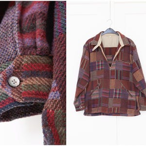Op de afbeelding: Een bruin, rood en paars geruit jack met een ritssluiting. Het jack heeft een patchwork-ontwerp en een kraag.