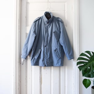 May include: A light blue jacket with a zip fastening, two flap pockets, and a stand-up collar.