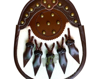 May include: A white leather sporran with brown leather trim and tassels. The sporran has a circular flap with decorative stitching and brass studs.