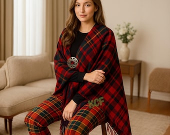 May include: A woman wearing a red, green, and navy plaid shawl secured with a decorative brooch. Matching plaid pants are also worn. The shawl has a fringed edge and the initials "KCF" are embroidered on the pants.
