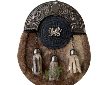 May include: A brown fur sporran with a silver metal top and decorative accents. The sporran features a black leather center with a gold dragon emblem and three hanging tassels.