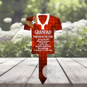 Puede incluir: Una estaca de jardín con forma de camiseta de fútbol roja y blanca con el texto "GRANDAD FOREVER ON THE TEAM". La estaca presenta un balón de fútbol con alas y un poema. La estaca está hecha de un material duradero y está diseñada para uso en exteriores.