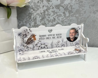 May include: A white wooden miniature bench memorial featuring a robin illustration, floral patterns, and the text "Robins appear when loved ones are near" and "Until we meet again Michael". A circular photograph of a man is printed on the backrest.
