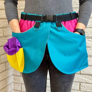 May include: A turquoise, pink and yellow utility belt with multiple pockets and a black adjustable belt.