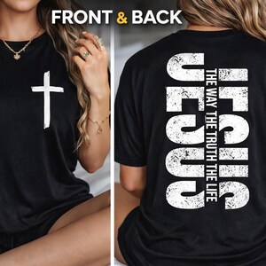 May include: Black t-shirt with a white cross on the front and the word "JESUS" vertically on the back, along with the text "THE WAY THE TRUTH THE LIFE". The shirt is a classic crew neck style.