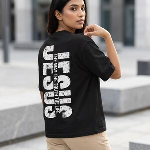 May include: Black t-shirt with the word "JESUS" printed vertically in white, along with the phrase "THE WAY THE TRUTH THE LIFE." The shirt is a classic crew neck style.