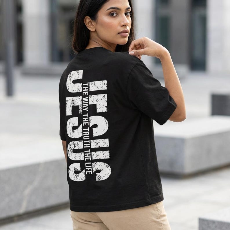May include: Black t-shirt with the word "JESUS" printed vertically in white, along with the phrase "THE WAY THE TRUTH THE LIFE." The shirt is a classic crew neck style.