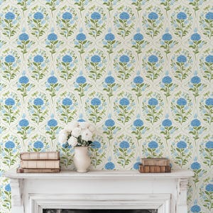 May include: Floral wallpaper featuring a repeating pattern of blue hydrangeas, green leaves, and dragonflies on a cream background. The image also shows a white mantel with books and a vase of white flowers.