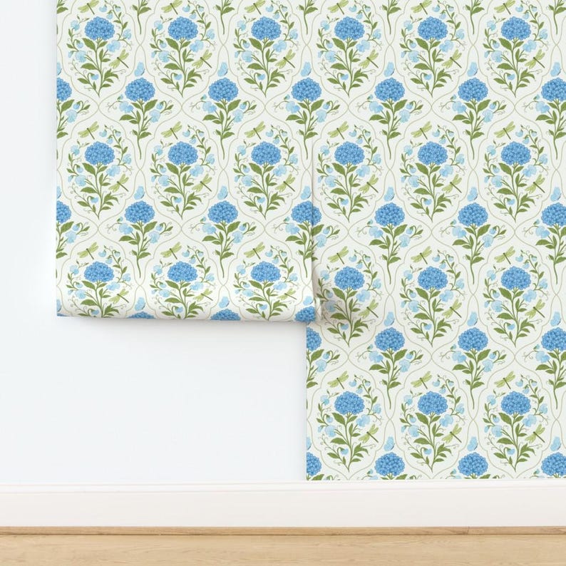 May include: Wallpaper roll featuring a repeating pattern of blue hydrangea flowers, green leaves, and dragonflies on a cream background. The design is arranged in an oval trellis pattern, creating a classic and elegant look.