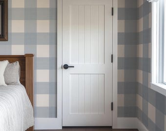 May include: A white interior door featuring a vertical plank design with two distinct panels and a matte black lever handle. The door is mounted with three black hinges and is set within a white frame against a blue and white buffalo check wall.