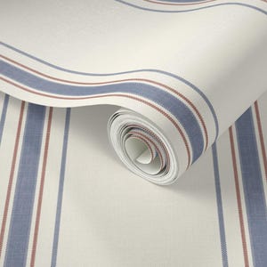 May include: A roll of wallpaper with a cream-colored background and vertical stripes in blue and red. The stripes vary in width, with the blue stripes being wider and the red stripes being thinner. The wallpaper is partially unrolled, revealing the rolled-up portion.