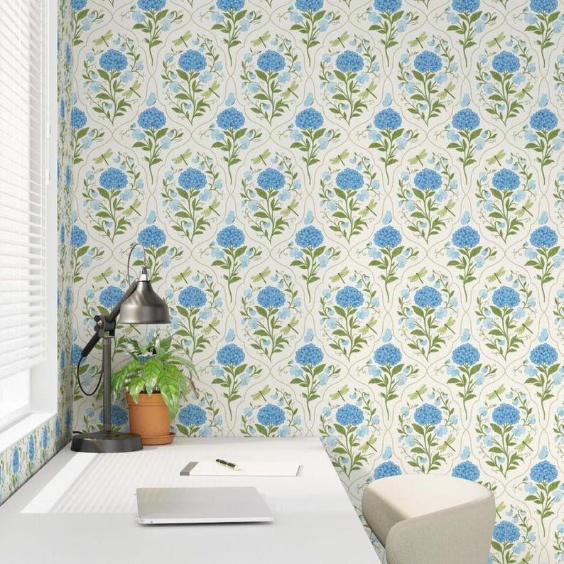 May include: Floral wallpaper featuring a repeating pattern of blue hydrangea blooms, green leaves, and delicate dragonflies on a cream background. The design includes a subtle, curved trellis-like structure, creating a classic and elegant aesthetic. This wallpaper is suitable for interior design projects.