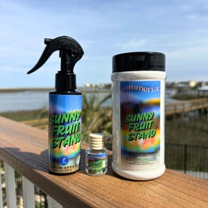 May include: Three bottles of "Sunny Fruit Stand" room spray, carpet freshener, and a small fragrance bottle. The room spray bottle has a black spray nozzle. The labels are blue with green and yellow text.