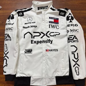 May include: White racing jacket with black accents and multiple sponsor logos, including "Expensify," "Tommy Hilfiger," and "IWC." The jacket features a stand-up collar, black cuffs, and the American flag. The jacket has the text "APXGP" on the sleeves.