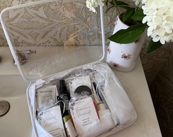 May include: A clear, rectangular plastic organizer case containing various personal care items in white tissue paper. The case features white trim and labels reading Personal Hygiene and Feminine Products, including Liners, Pads, and Tampons.