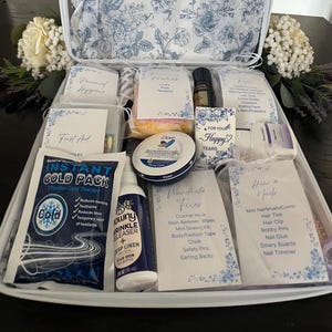 Puede incluir: Una maleta blanca llena de kits de cuidado personal organizados, que incluyen una compresa fr&iacute;a instant&aacute;nea, eliminador de arrugas Downy, crema Dove y varias bolsas etiquetadas para higiene, primeros auxilios y cuidado personal.