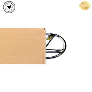 May include: A brown cardboard box with a chrome car emblem sticking out of the top. The emblem is a stylized letter V with a circle around it.