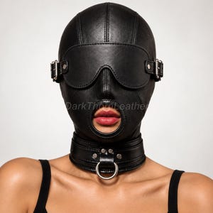 May include: A black leather hood featuring an integrated blindfold with silver-toned buckles on the sides, a circular opening for the mouth, and a matching collar at the base with a central silver-toned metal ring. The text DarkThornLeather is visible.