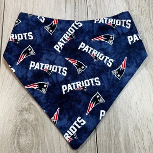 May include: A blue bandana with a white "Patriots" logo repeated throughout the fabric. The logo features a red, white, and blue football helmet.