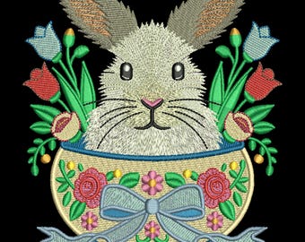 May include: Embroidered design of a white bunny rabbit peeking out of a basket with a blue bow. The basket is decorated with pink, red, and green flowers. The design is perfect for Easter crafts.