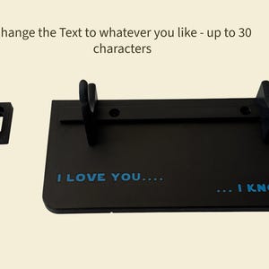 May include: Black display stand with the text "I LOVE YOU.... ... I KNOW" in blue. The stand has two upright supports and a separate mounting bracket. The text "Change the Text to whatever you like - up to 30 characters" is above the stand.