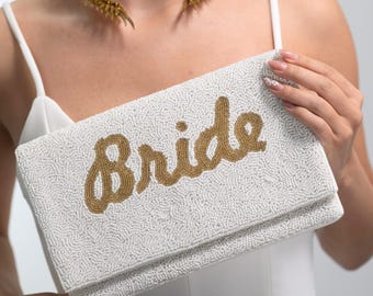 May include: White beaded clutch with a gold beaded "Bride" inscription.
