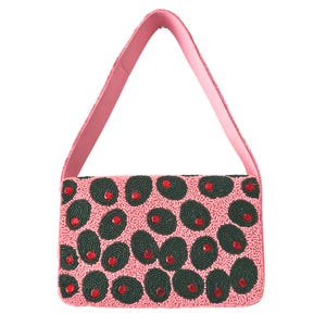 May include: A pink beaded handbag with a matching pink strap. The bag is covered in dark green oval beads with red bead accents, creating a pattern. The bag is rectangular in shape.