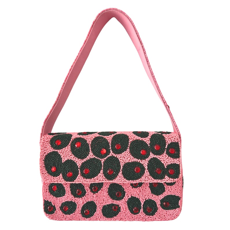 May include: A pink beaded handbag with a matching shoulder strap. The bag features a pattern of dark green ovals with red accents. The bag is rectangular with a flap closure.