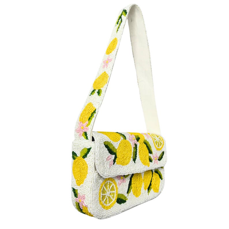 May include: White beaded shoulder bag with a flap closure, adorned with yellow lemon and pink flower designs. The strap is white, and the bag features a repeating pattern of lemons and flowers.