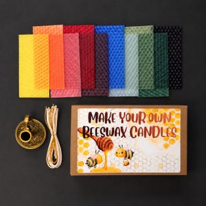 May include: A DIY beeswax candle making kit featuring a rectangular cardboard box with the text "MAKE YOUR OWN BEESWAX CANDLES," a bundle of cotton wicks, a gold-toned metal candle holder, and eleven rectangular sheets of textured beeswax in colours.