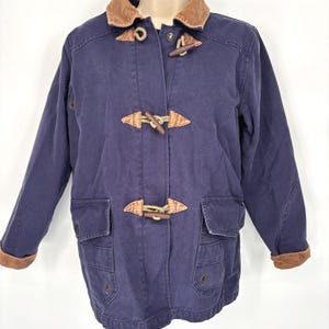 May include: A navy blue toggle coat with a brown corduroy collar and cuffs. The coat features wooden toggle closures and two front pockets. The coat is a classic style, suitable for cooler weather.